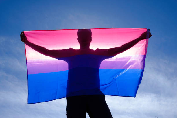erwachsener mann auf dem rücken mit bisexueller flagge an einem sonnigen tag. - bi sexual stock-fotos und bilder