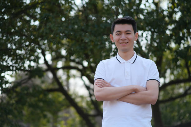 istock Chinese young man smiling and looking at camera in green park 1396033801