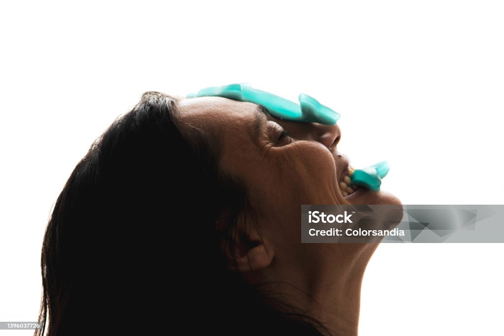 woman with candy gummies on the face. backlit woman eating jelly beans and balancing with jelly beans on her face 40-44 Years Stock Photo