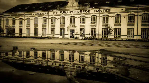 Magnificent building of a old factory in Nantes "Les Chantiers de Nantes" wide shot with a reflection in a puddle of water, warm dominant color