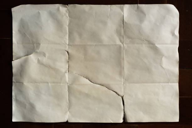 Old off white folded paper on dark wood background