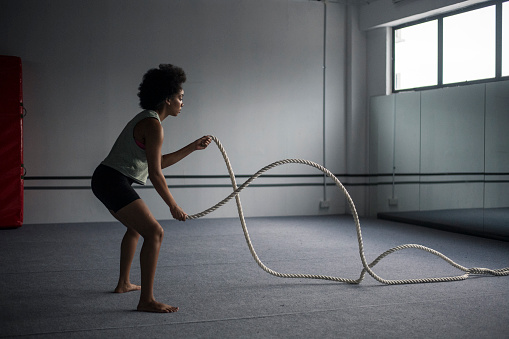 African American woman working out with battle ropes in a gym