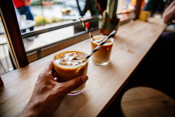 istock Man holding iced latte on wooden table 1396044265