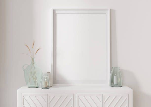 istock Empty vertical picture frame standing on white sideboard. Mock up interior in contemporary style. Free, copy space for picture, poster. Console, vase with dried plants. Close up. 3D rendering. 1396045545
