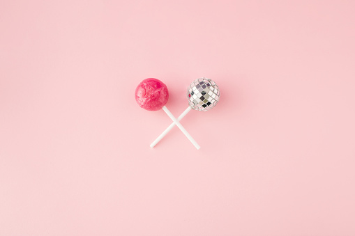 Lollipop candy and disco ball on lollipop stick on pink background. Flat lay. Top view. Minimal concept.