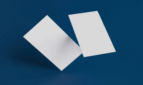 Photo of Two white business cards on a blue background falling in blank space