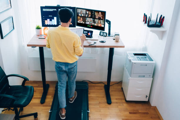 uomo alla scrivania in piedi home office che parla in videochiamata aziendale - colleague looking at camera indoors lifestyles foto e immagini stock