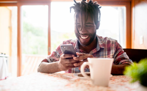 istock Young man sitting at home texting on his phone over coffee 1396053031
