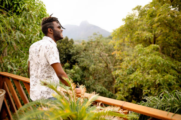 istock Young man smiling while looking at a scenic forest view from a balcony 1396053068