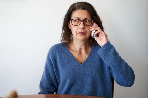 Concepto de fraude telefónico para personas mayores. Mujer madura que desconfía de la llamada telefónica photo