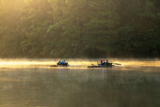 mae hong son, thailand-okt, 2021: bambus-rafting am pangung-see in mae hong son, nördlich von thailand. schwebend im wasser und gekuschelt von mildem nebel und sanftem licht des sonnenlichts am morgen. - open stock-fotos und bilder