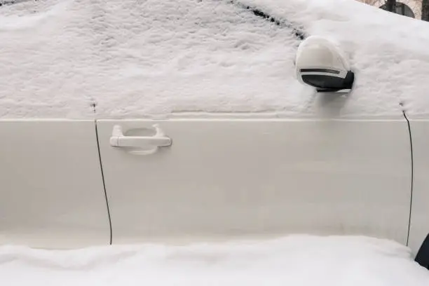 Cropped white car covered snow in winter season. Side view