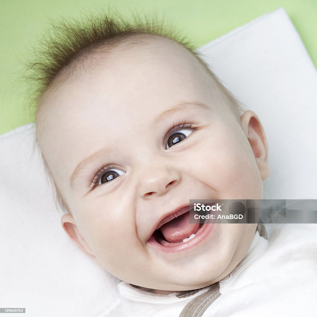 A young baby smiling showing first teeth Close up of adorable 6 months old baby laughing Number 1 Stock Photo
