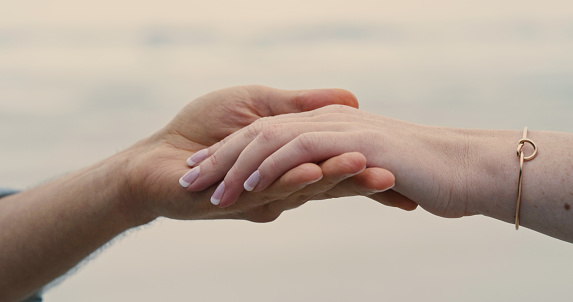 Una pareja irreconocible cogida de la mano y con un anillo de compromiso. Primer plano de un hombre y una mujer tras su propuesta en la playa photo