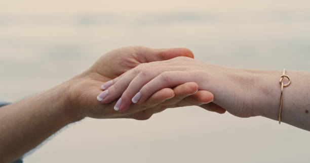 An unrecognizable couple holding hands and wearing an engagement ring. Closeup of a man and woman after their proposal at the beach An unrecognizable couple holding hands and wearing an engagement ring. Closeup of a man and woman after their proposal at the beach eloping stock pictures, royalty-free photos & images