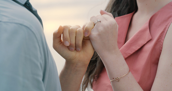 手をつないで婚約指輪をはめている見分けがつかないカップル。ビーチでプロポーズした後の男女のクローズアップ