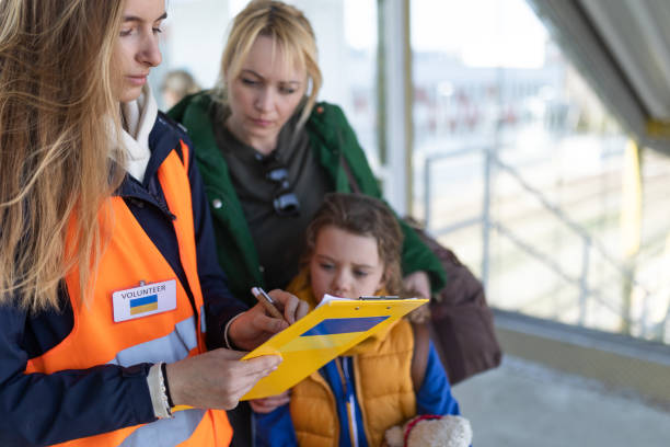 volunteer filling form for ukrainian refugees at train station. - assistência em catástrofes imagens e fotografias de stock