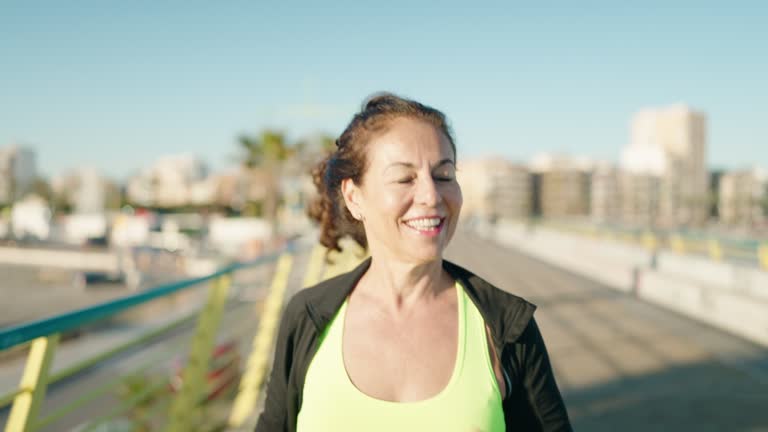 Middle age woman wearing sportswear smiling confident running at street