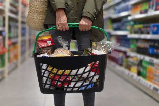 frau, die im supermarkt einkauft, trägt einen vollen einkaufskorb, nahaufnahme. - food bread groceries basket stock-fotos und bilder