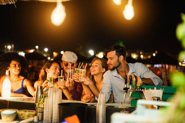 amigos felizes aplaudindo e bebendo coquetéis em festa ao ar livre - foco suave no rosto do homem direito - party nightclub night toast - fotografias e filmes do acervo