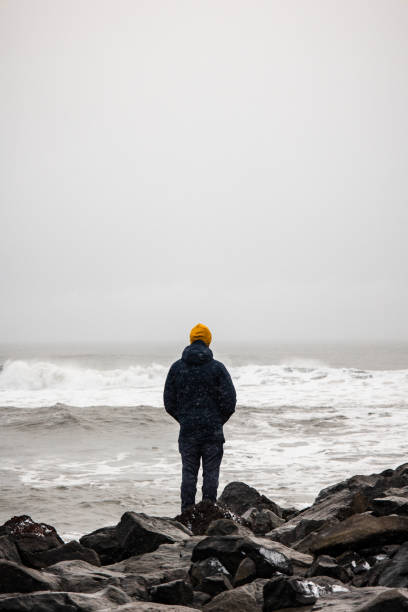 A man standing on the pier and looking on the storm waves in the Atlantic Ocean in Iceland in winter