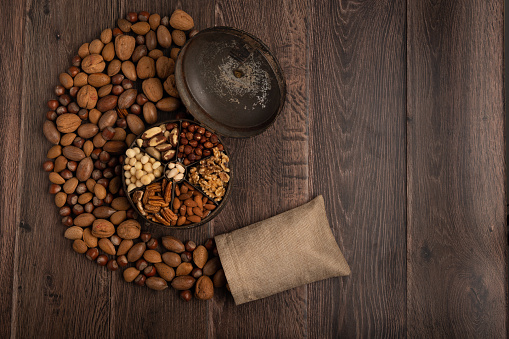 Mixed nuts  in a hessian bag and container on a dark wood background