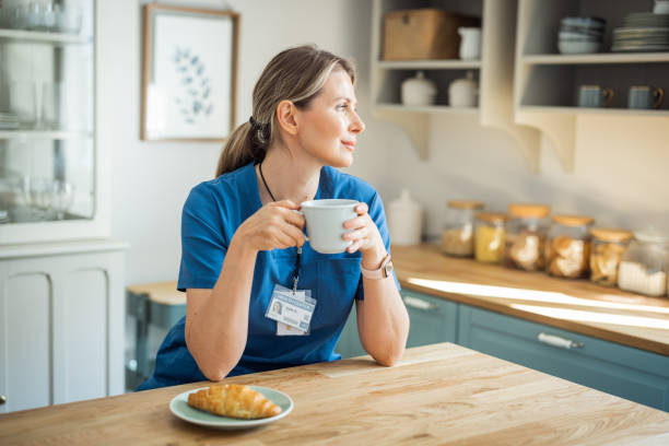 Female doctor at home. Drinking tea at kitchen and resting after work shift.