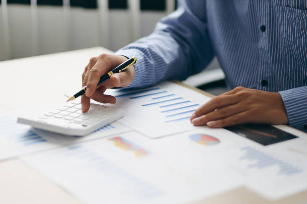 istock Accountant or banker working process, a Businessman using a calculator to calculate the numbers of statistic business profits growth rate on documents graph data in the desk office. 1396067808