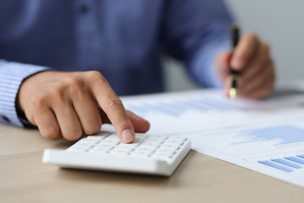 istock Accountant or banker working process, a Businessman using a calculator to calculate the numbers of statistic business profits growth rate on documents graph data in the desk office. 1396067828