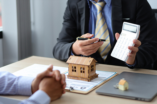 Real estate agent discussing about the terms of the purchase agreement and sign the documents to make the contract legally. Home sales, renting, leasing, mortgage and home insurance concept.