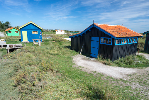Multi-coloured wooden fishing cabins for oyster farming standing in tidal salt marsh on Oléron Island Charente-Maritime, France