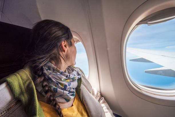 istock Woman flying in airplane, looking through window. Going on vacation. 1396070628