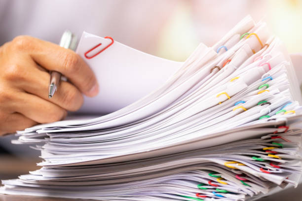 istock hands of a man in a white shirt searching for contract agreement documents in Stack of Group report papers clipped in color clips in fair light 1396070673