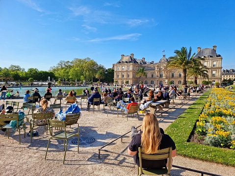 The Jardin du Luxembourg (Luxembourg Garden), is located in the 6th arrondissement of Paris, France. Creation of the garden began in 1612. The image shows people relaxing in the gardens during a warm day in springtime.