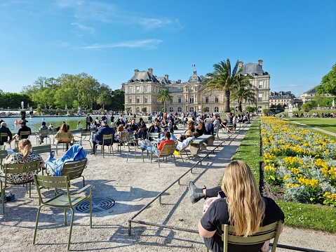 The Jardin du Luxembourg (Luxembourg Garden), is located in the 6th arrondissement of Paris, France. Creation of the garden began in 1612. The image shows people relaxing in the gardens during a warm day in springtime.