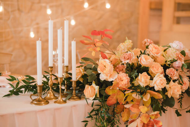istock Table setting at wedding reception. Floral compositions with beautiful flowers and greenery, candles, laying and plates on decorated table. 1396071823
