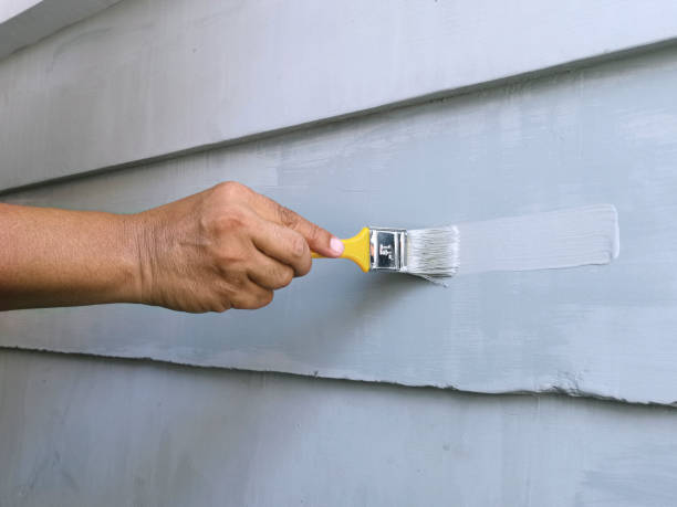 istock Hand holding brush painting wall 1396072357