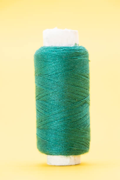 istock single Dark Cyan color yarn or spool thread over on yellow background 1396073615