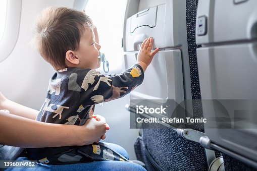 istock Baby traveling in airplane flying sitting on his mother lap in the aircraft 1396074982