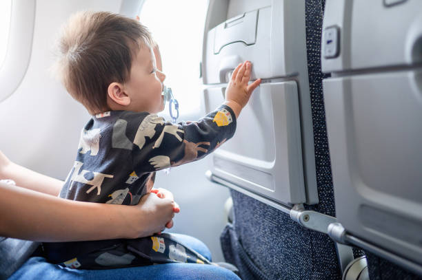 Baby traveling in airplane flying sitting on his mother lap in the aircraft stock photo