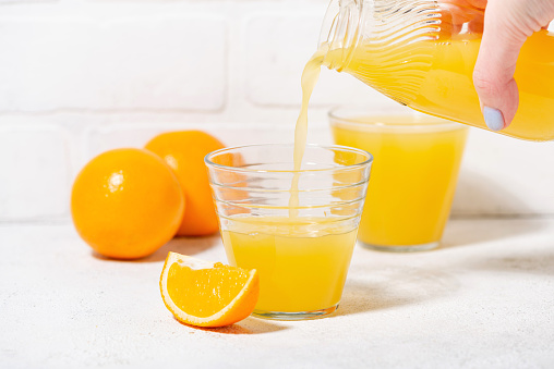 Orange Juice being poured into Glass against White Background