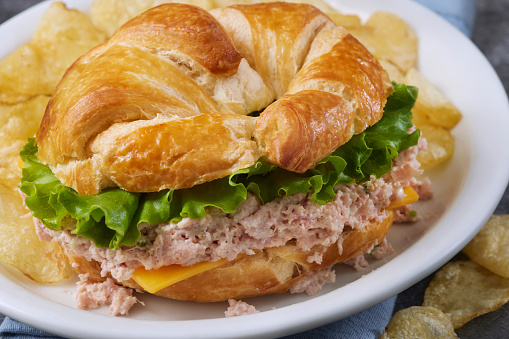 Classic Retro Style Deviled Ham Salad Sandwich on Croissant with Cheddar Cheese, Lettuce and Potato Chips