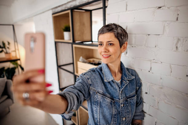 istock Smiling young woman taking a selfie at home 1396082512