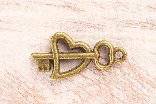 Bronze vintage antique key on brown wooden background. Old keys concept
