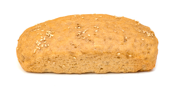 Loaf of seed bread accompanied by a bowl of nuts and walnuts in front of the product on a tabal of bars of two colors of wood.