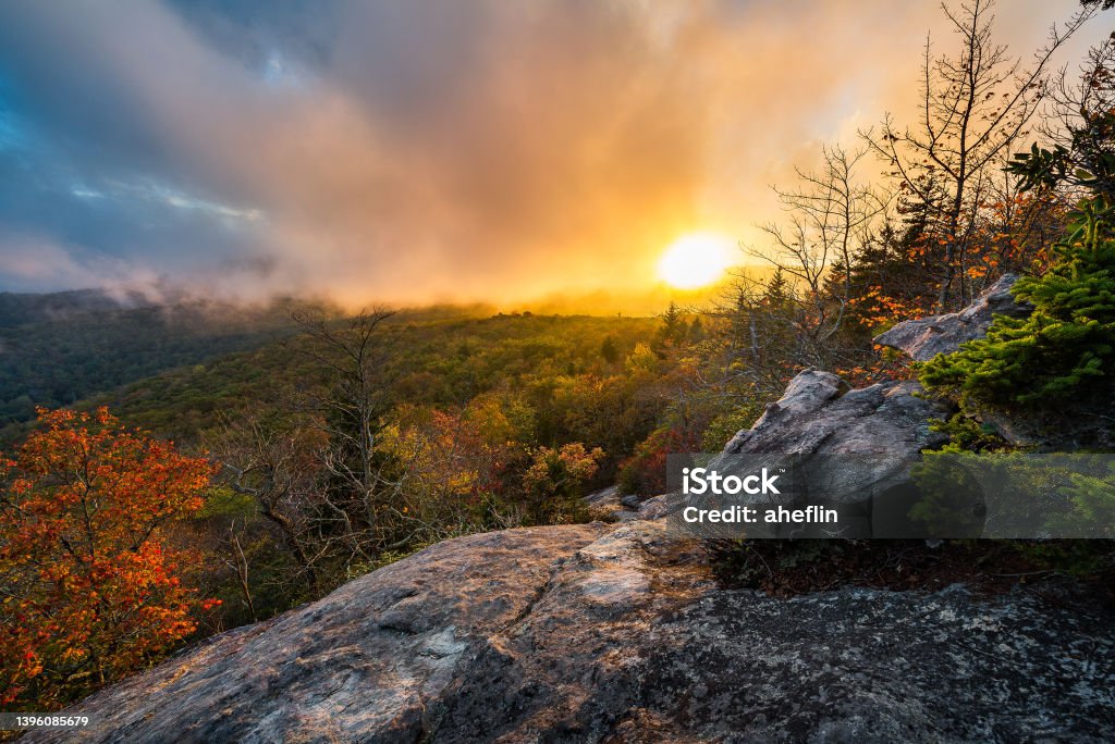 An autumn sunset through fog over the Blue Ridge Mountains Evening sun breaks through the fog and illuminates an autumn landscape along the Blue Ridge Parkway in North Carolina Blue Ridge Mountains Stock Photo