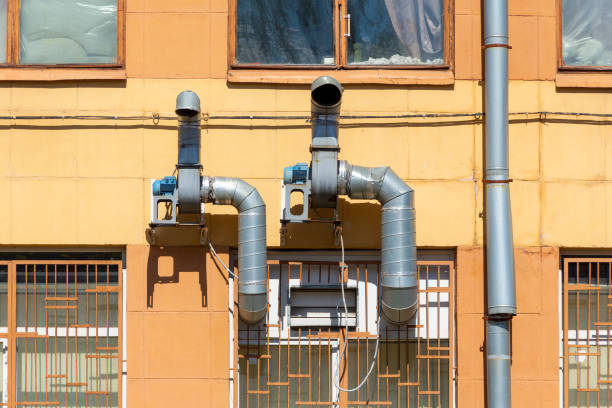 Ventilation unit with electric motor and metal pipes on the facade of the building