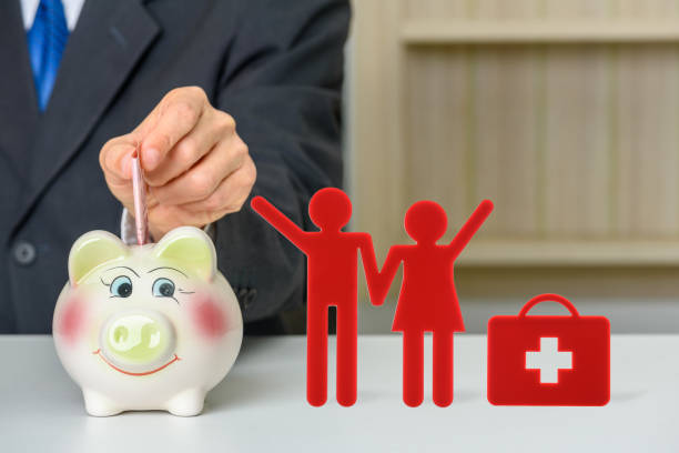 Saving money for family health insurance or for a couple life, healthcare concept : Patient save money in a piggy bank with a red man and woman and a suitcase, depicts saving money on health expense. ahorrar dinero para el seguro de salud familiar o para una vida de pareja, concepto de atención médica: el paciente ahorra dinero en una alcancía con un hombre y una mujer rojos y una maleta, representa ahorrar dinero en gastos de salud.