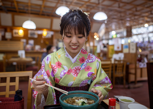 Japanese woman in kimono eating soba in traditional Japanese restaurant