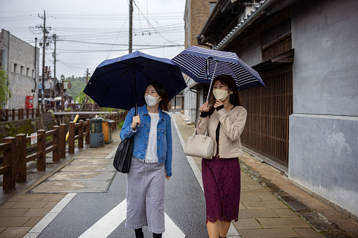 Happy young couple standing under an umbrella and looking around the city.